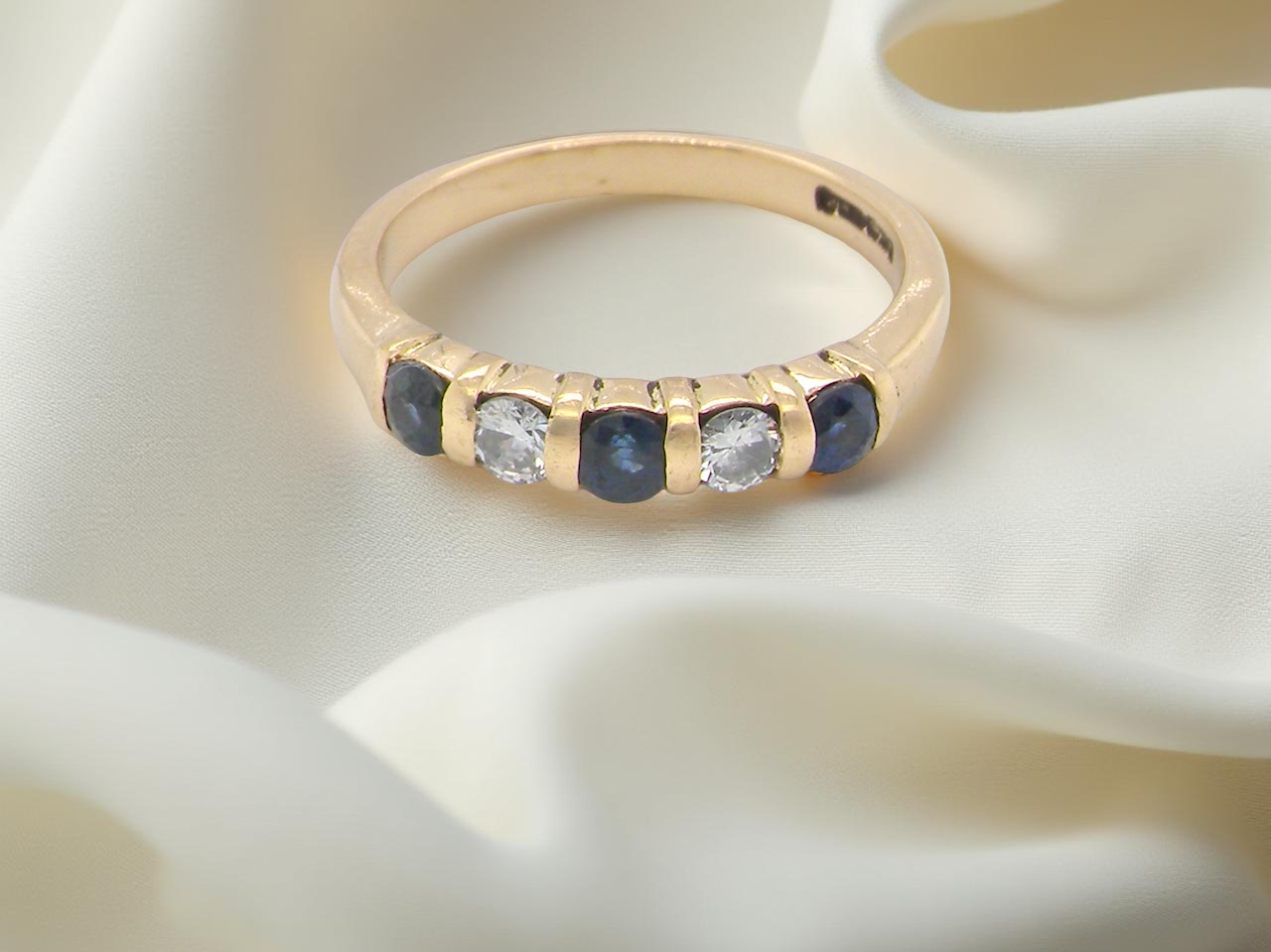 18-carat gold half-hoop eternity ring, set with round mid-blue sapphires