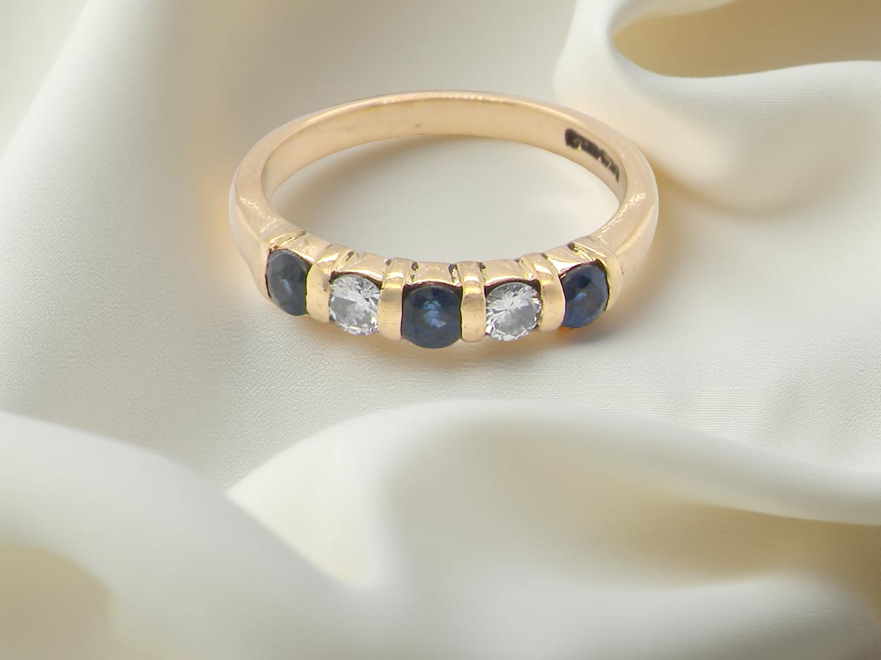 18-carat gold half-hoop eternity ring, set with round mid-blue sapphires