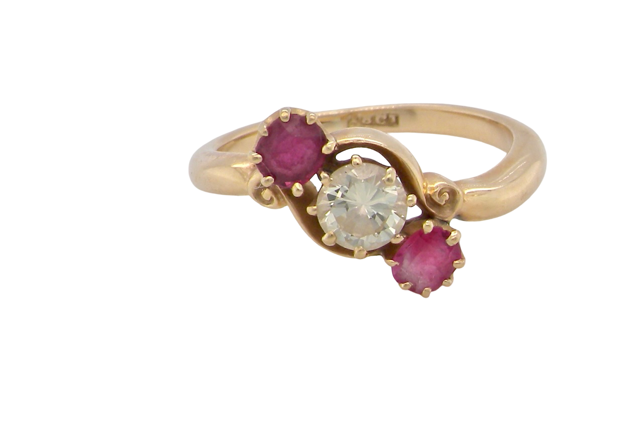 Gold ring with a central diamond and two rubies on a white background