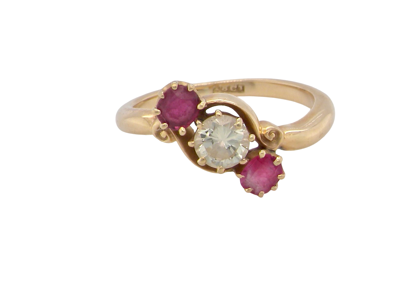 Gold ring with a central diamond and two rubies on a white background