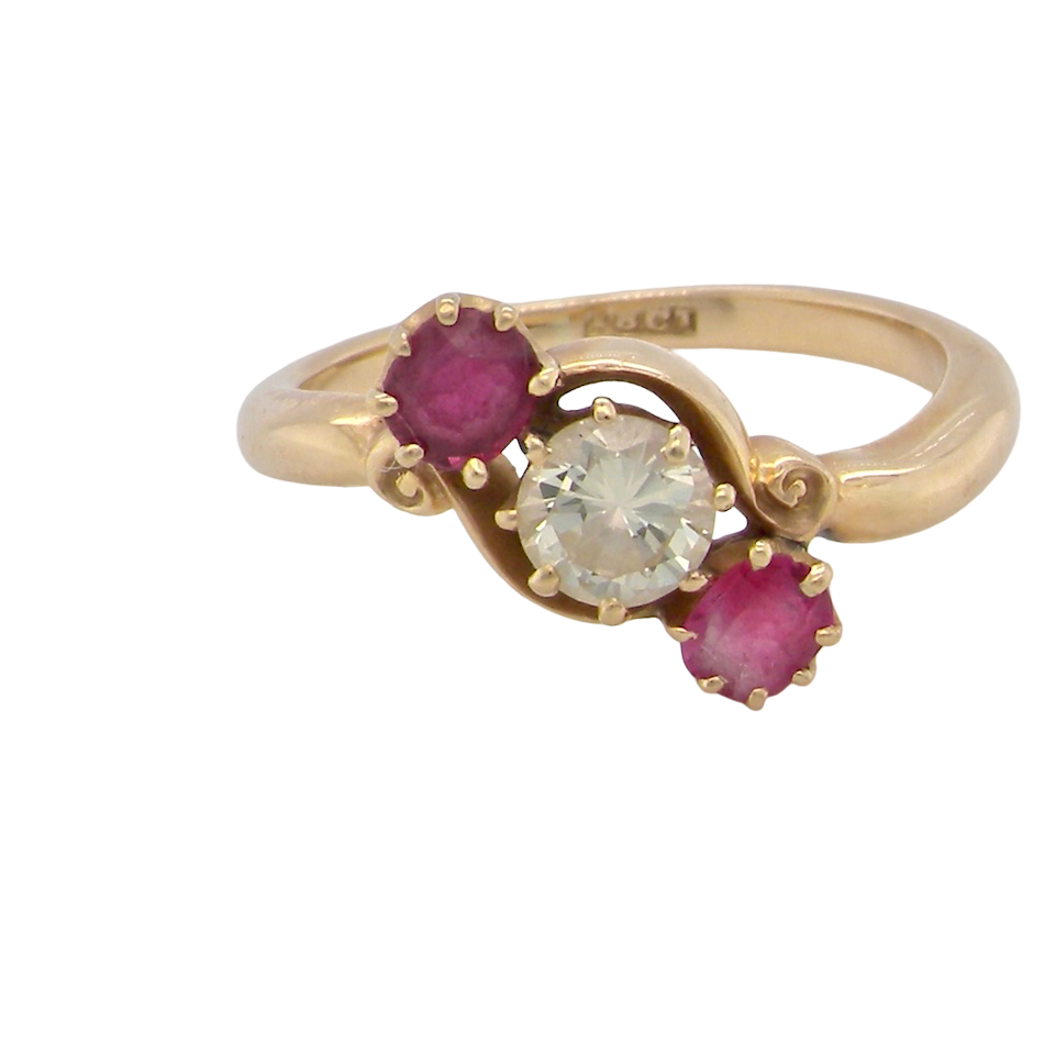 Gold ring with a central diamond and two rubies on a white background