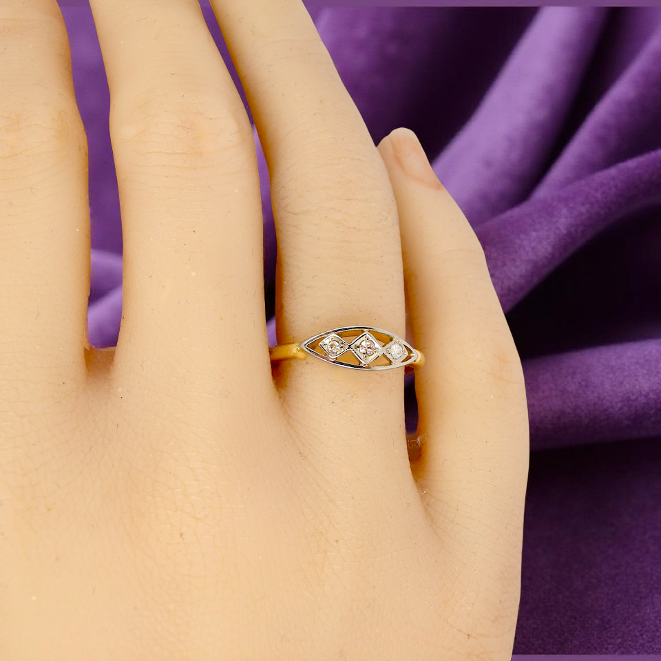 Gold ring with diamonds on a hand against a purple fabric background