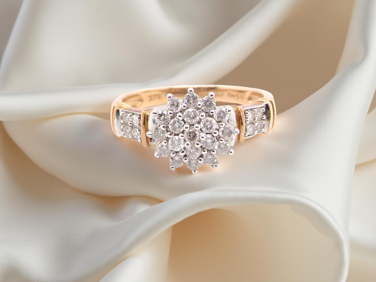 A modern 9 carat gold cluster ring featuring a round head fully set with nineteen brilliant-cut diamonds,