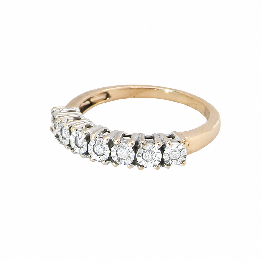 9 carat gold eternity ring.
Set with seven small white diamonds, each 1.8mm within an illusion setting that is 3.8mm in diameter, and white gold. 
