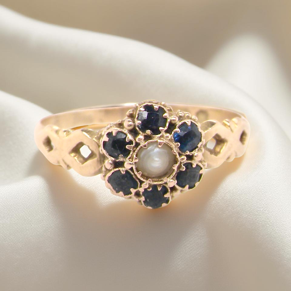 A 15 carat gold dress ring. The centre a small seed pearl, 3mm diameter. Surrounded by 6 sapphires,