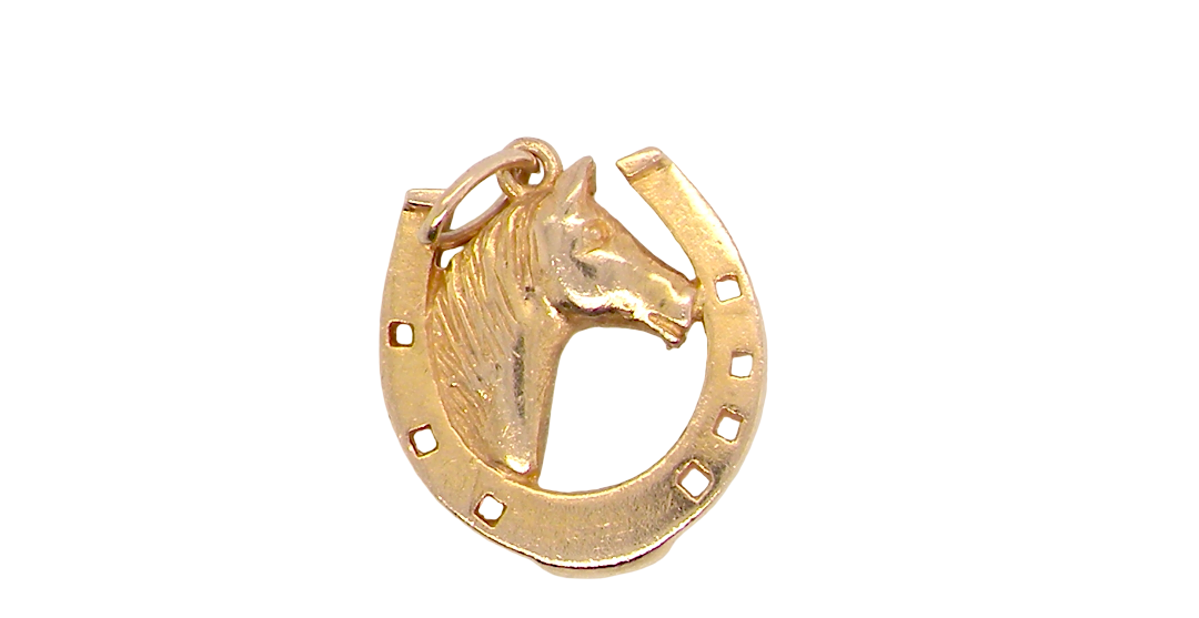 A 9 carat gold charm in the shape of a horseshoe with a horses head profile to the centre.