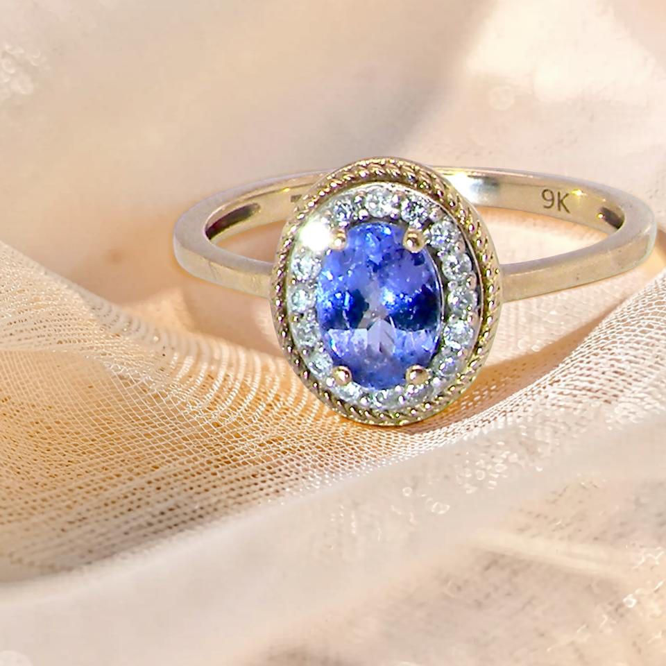 A 9 carat gold cluster ring. Features to the centre an oval cut tanzanite gem stone. Measures 7x5mm, claw setting.