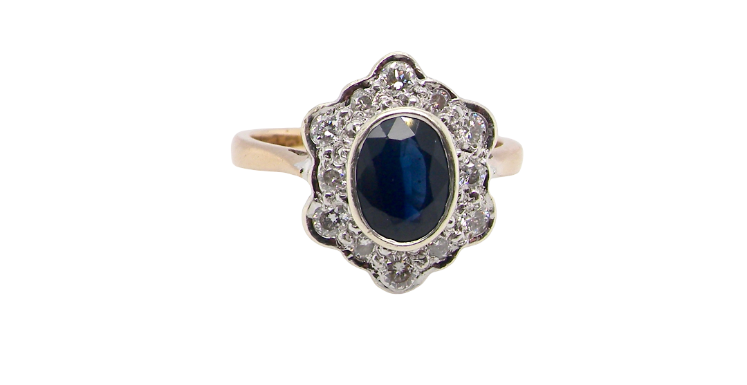 A 9 carat gold cluster ring that features an inky black blue oval cut sapphire. This measures 8x6mm