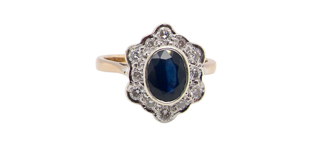A 9 carat gold cluster ring that features an inky black blue oval cut sapphire. This measures 8x6mm