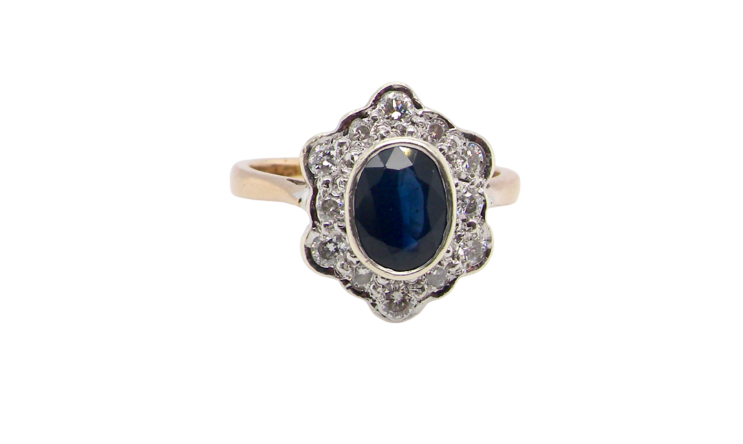 A 9 carat gold cluster ring that features an inky black blue oval cut sapphire. This measures 8x6mm