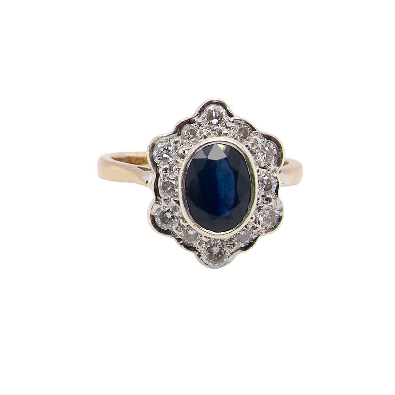 A 9 carat gold cluster ring that features an inky black blue oval cut sapphire. This measures 8x6mm