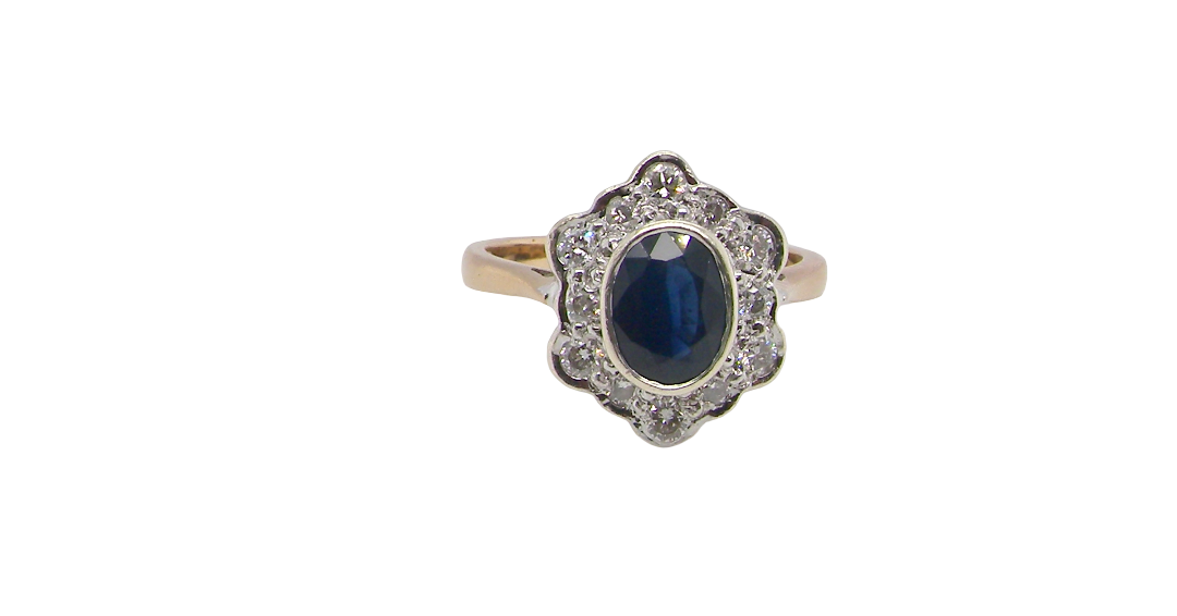 A 9 carat gold cluster ring that features an inky black blue oval cut sapphire. This measures 8x6mm in a safe rim style setting