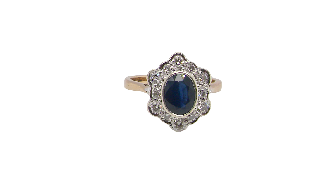 A 9 carat gold cluster ring that features an inky black blue oval cut sapphire. This measures 8x6mm in a safe rim style setting