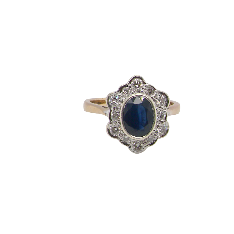 A 9 carat gold cluster ring that features an inky black blue oval cut sapphire. This measures 8x6mm in a safe rim style setting