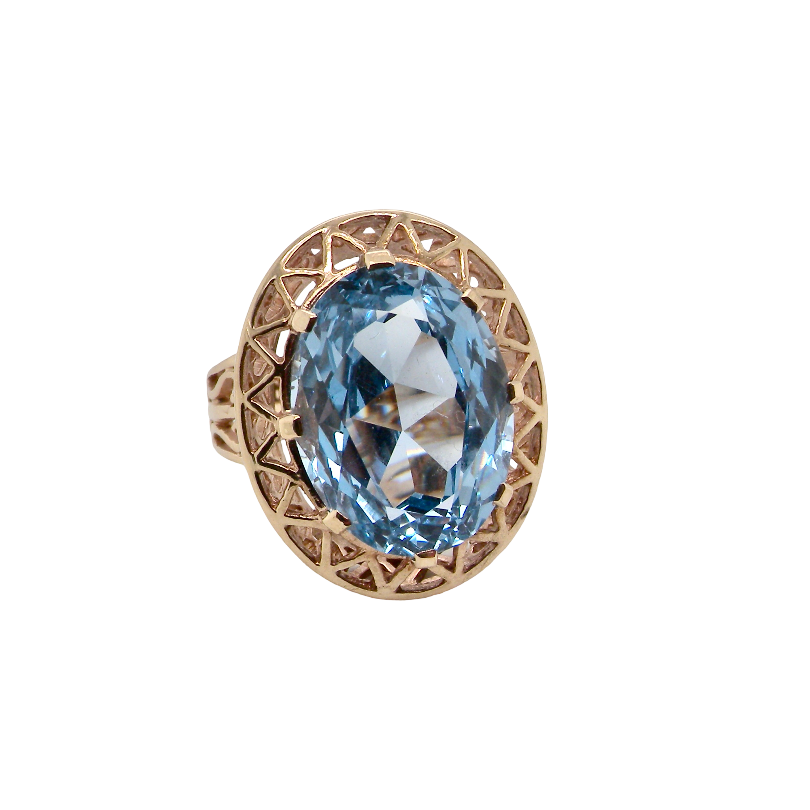 An oval-cut light blue gemstone ring set in a rose gold filigree halo, shown on a plain white background.