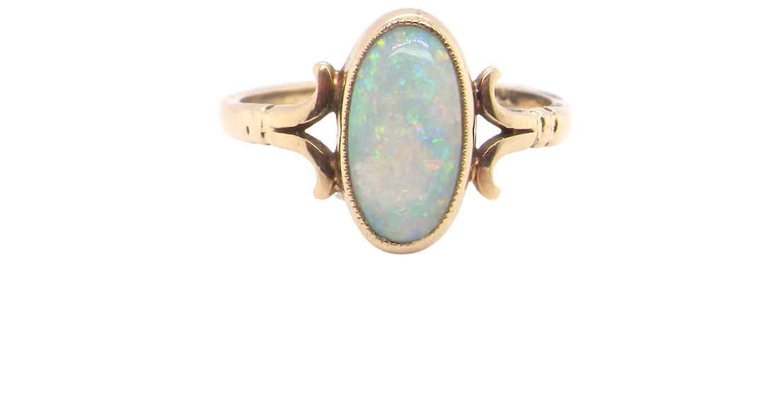 A 9 carat gold dress ring that features an oval shaped opal. Measures 12x6.7mm, with a very good play of colour across the white background.