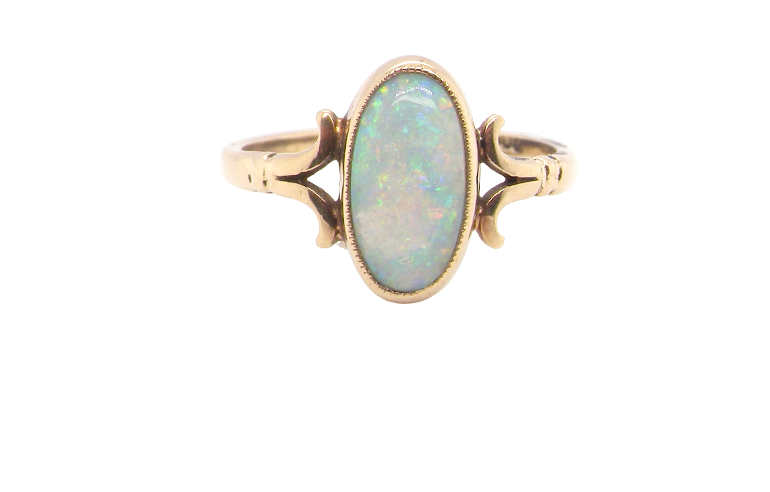 A 9 carat gold dress ring that features an oval shaped opal. Measures 12x6.7mm, with a very good play of colour across the white background.