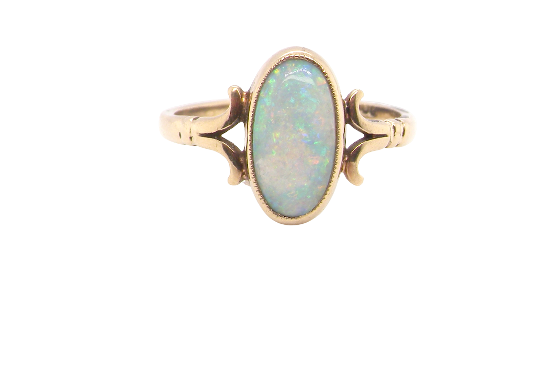 A 9 carat gold dress ring that features an oval shaped opal. Measures 12x6.7mm, with a very good play of colour across the white background.