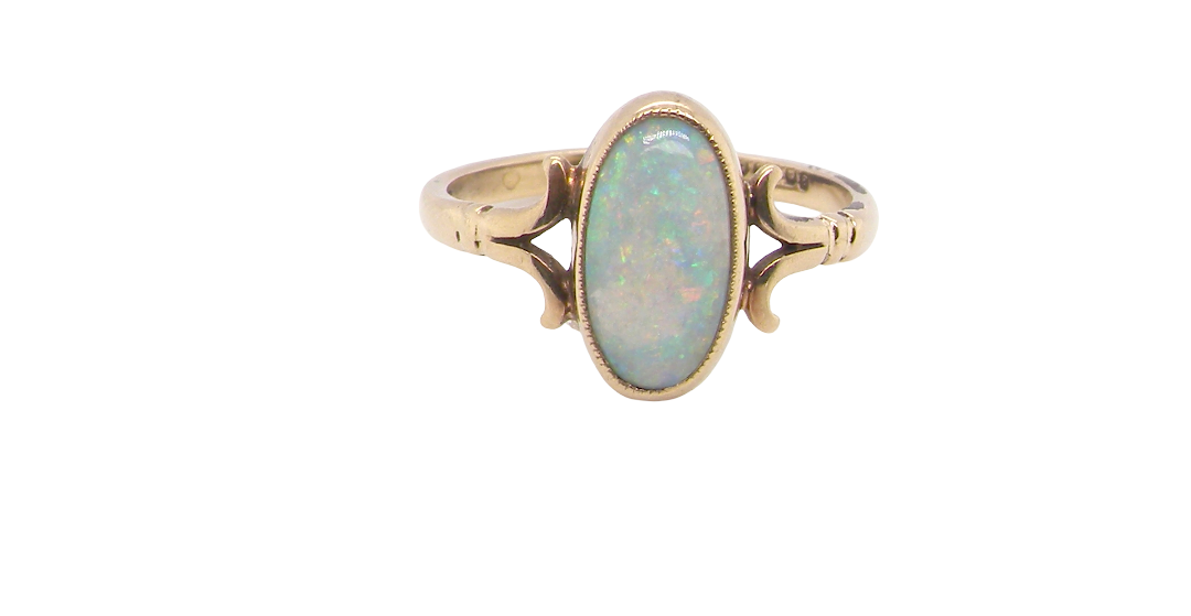 A 9 carat gold dress ring that features an oval shaped opal. Measures 12x6.7mm, with a very good play of colour across the white background. Mille grain setting