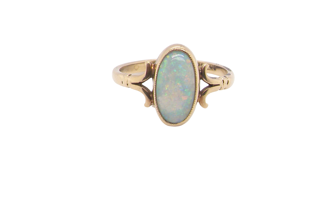 A 9 carat gold dress ring that features an oval shaped opal. Measures 12x6.7mm, with a very good play of colour across the white background. Mille grain setting