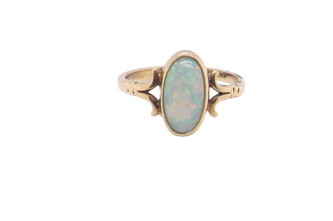 A 9 carat gold dress ring that features an oval shaped opal. Measures 12x6.7mm, with a very good play of colour across the white background. Mille grain setting