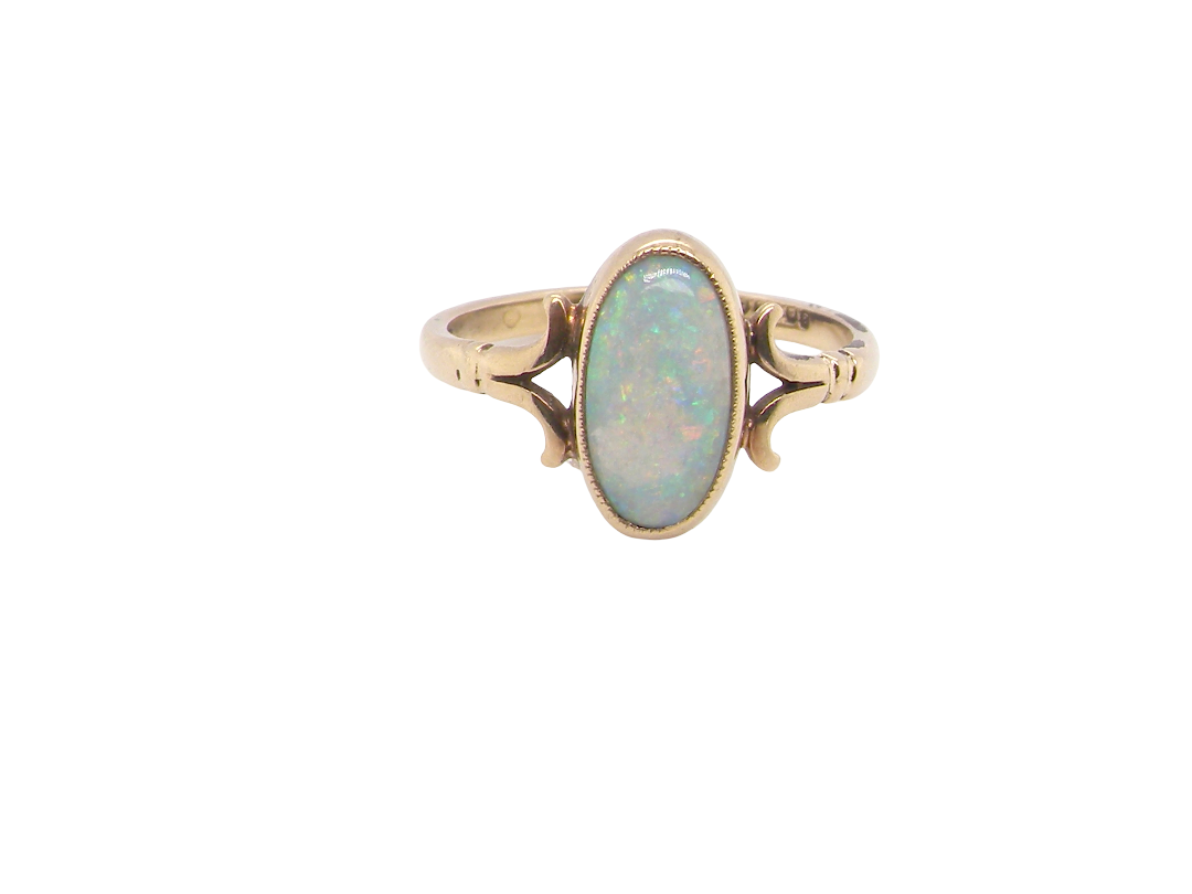 A 9 carat gold dress ring that features an oval shaped opal. Measures 12x6.7mm, with a very good play of colour across the white background. Mille grain setting