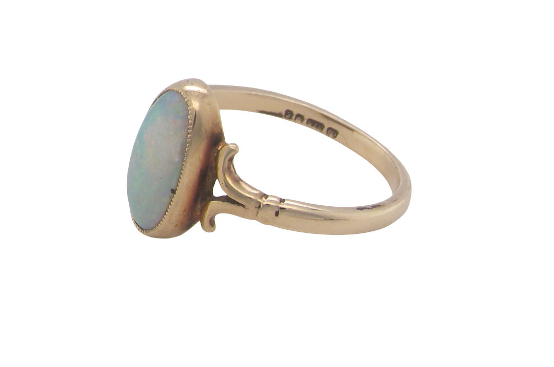 A 9 carat gold dress ring that features an oval shaped opal. Measures 12x6.7mm, with a very good play of colour across the white background. Mille grain setting
side angle