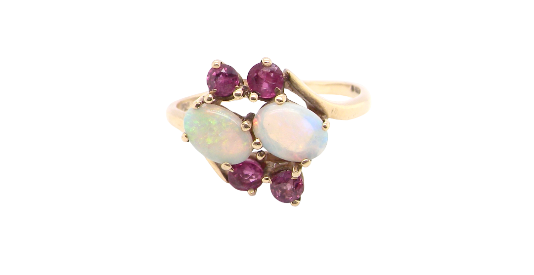 A 9 carat gold dress ring that features two oval white opals, each 7x5mm, and four rubies