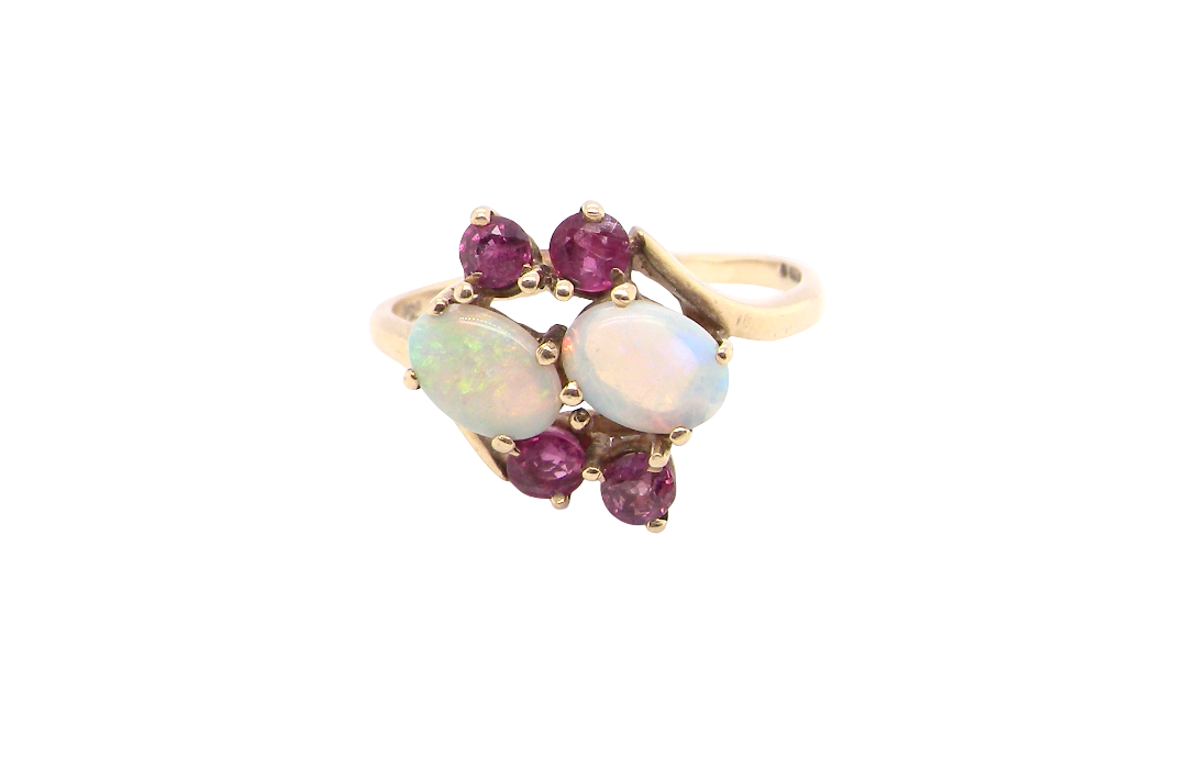 A 9 carat gold dress ring that features two oval white opals, each 7x5mm, and four rubies