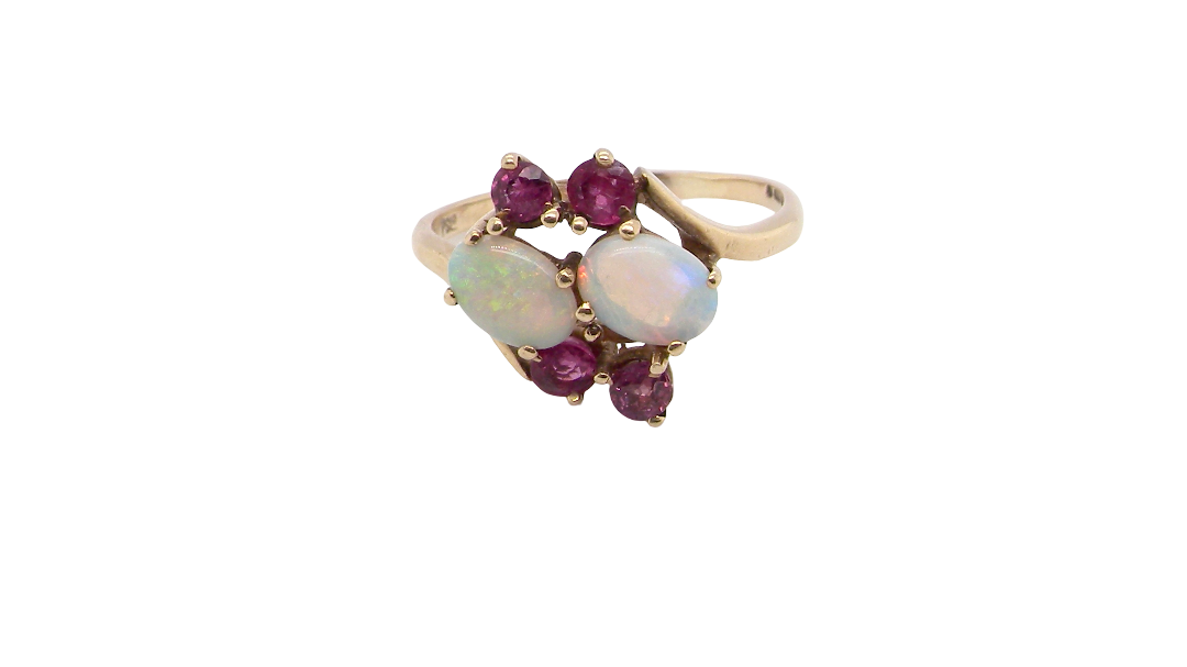A 9 carat gold dress ring that features two oval white opals, each 7x5mm, and four rubies each 3.4mm.