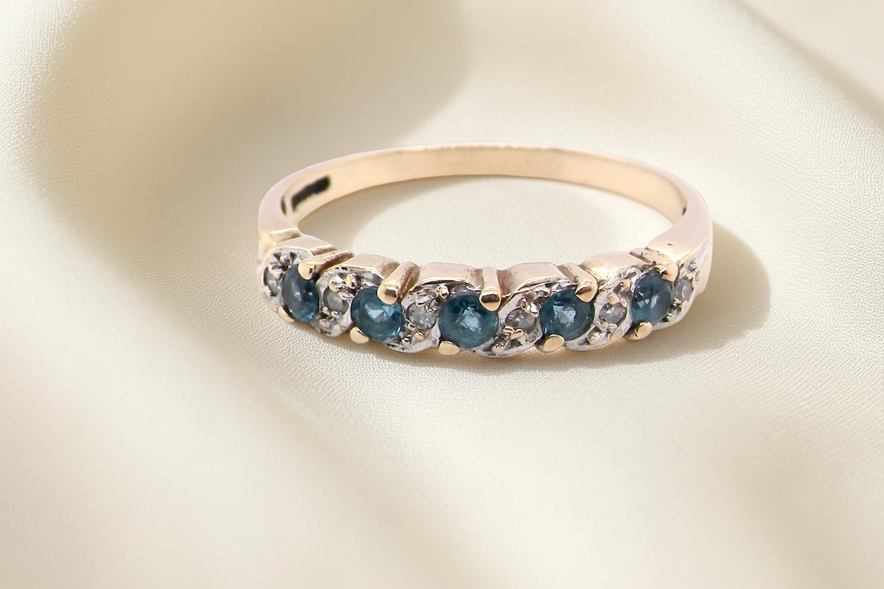 A 9 carat gold half hoop eternity ring. Set with five blue topaz gem stones, 2.8mm. 