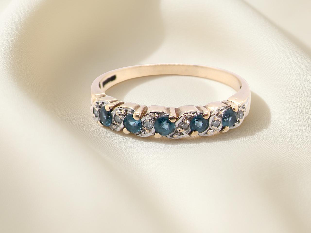 A 9 carat gold half hoop eternity ring. Set with five blue topaz gem stones, 2.8mm. 
