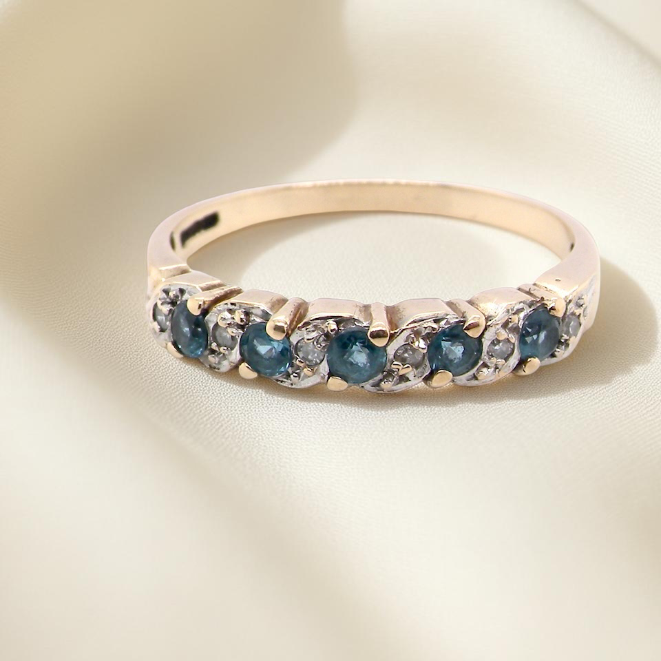 A 9 carat gold half hoop eternity ring. Set with five blue topaz gem stones, 2.8mm. 