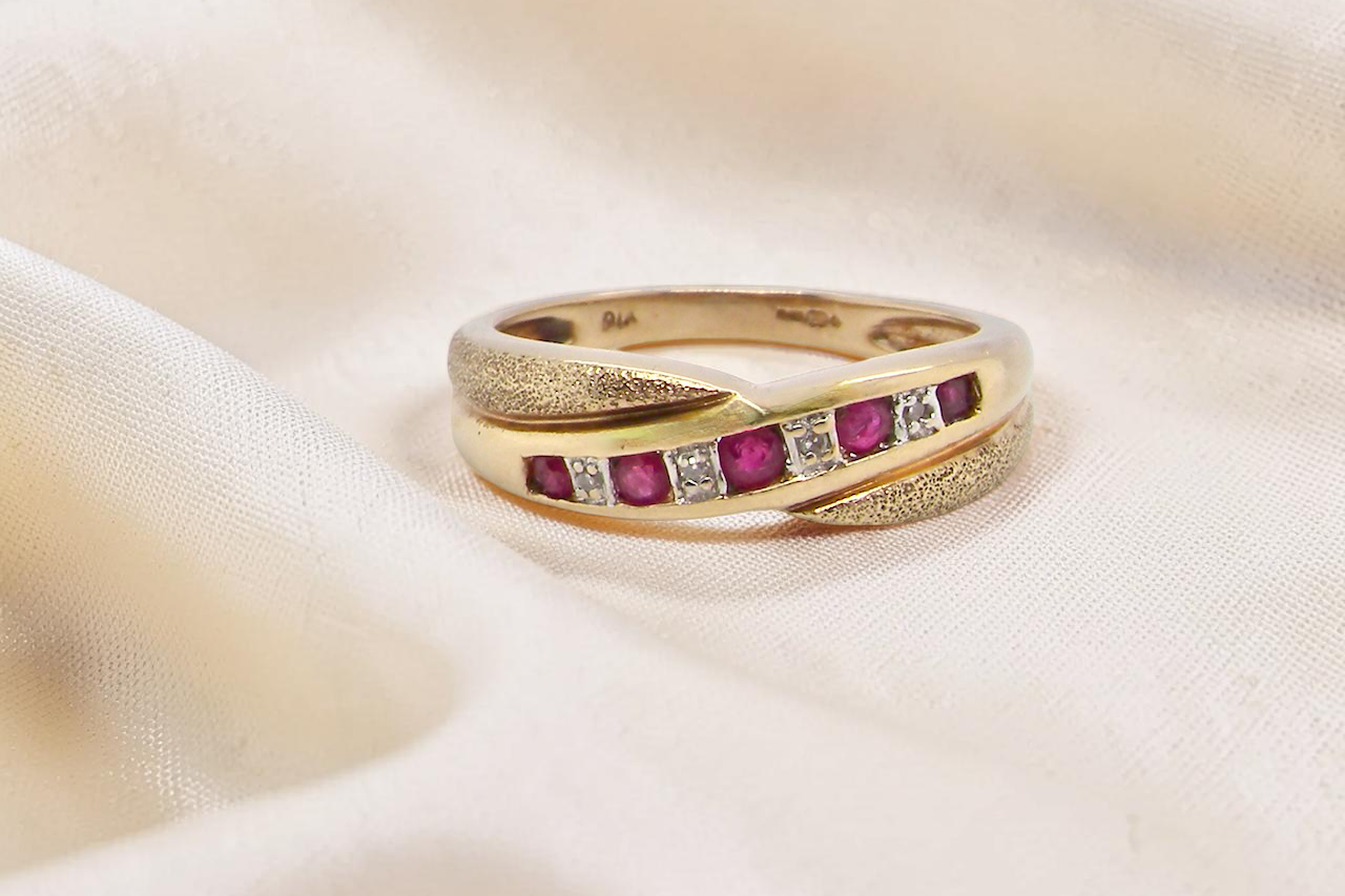 A 9 carat gold half hoop eternity ring. Set with five calibre cut rubies, from 1.7 to 2mm, and between 1mm white diamonds.