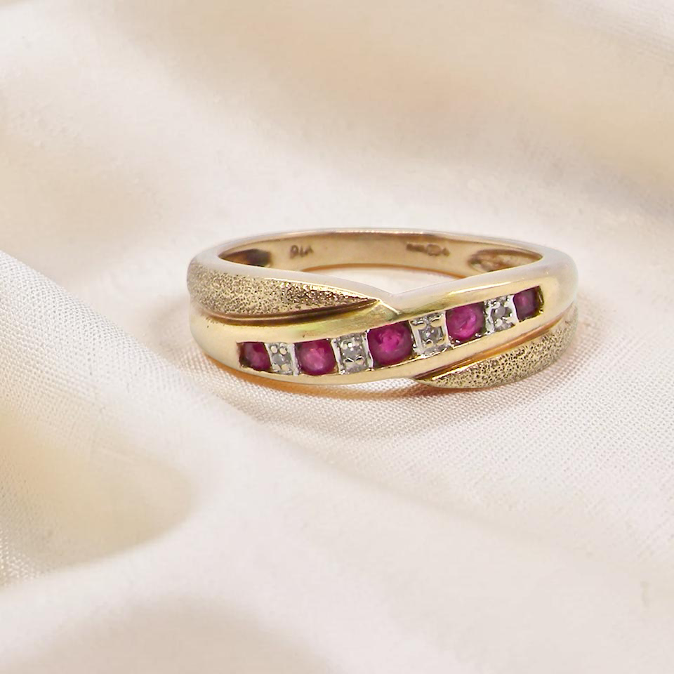 A 9 carat gold half hoop eternity ring. Set with five calibre cut rubies, from 1.7 to 2mm, and between 1mm white diamonds.
