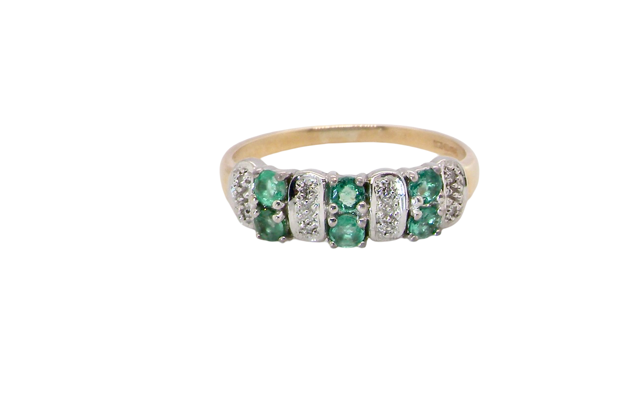A 9 carat gold half hoop ring. Set with six round emeralds 3mm each,(total 0.35 carats est) and interspaced with vertical white gold sections each set with 1mm diamonds.(0.05 carats est)