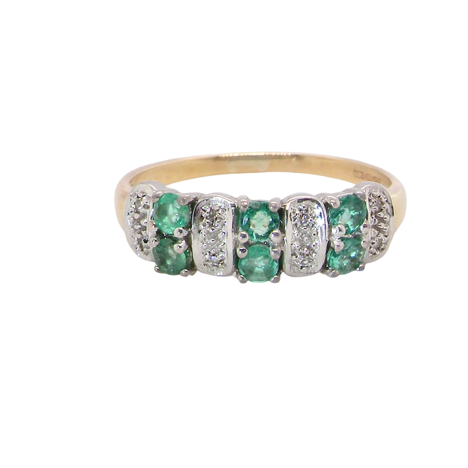 A 9 carat gold half hoop ring. Set with six round emeralds 3mm each,(total 0.35 carats est) and interspaced with vertical white gold sections each set with 1mm diamonds