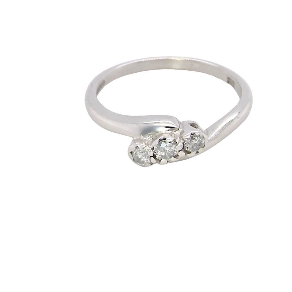 A 9 carat white gold cross over style trilogy ring. Three x 0.10mm diamonds, to an estimated at 0.30 carats.