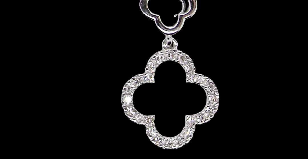 A 9 carat white gold pendant in the 'Alhambra' style. Set with twenty four small diamonds, carat total 0.12 carats.