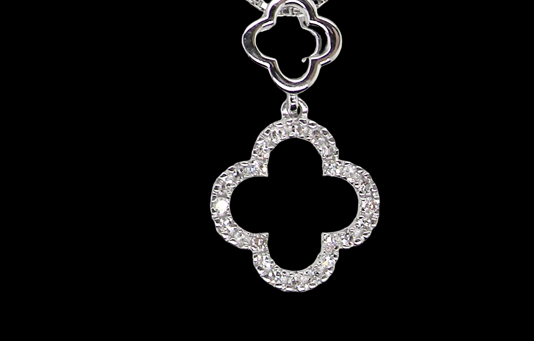 A 9 carat white gold pendant in the 'Alhambra' style. Set with twenty four small diamonds, carat total 0.12 carats.