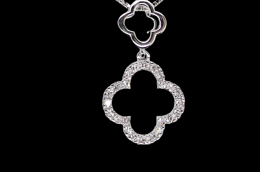 A 9 carat white gold pendant in the 'Alhambra' style. Set with twenty four small diamonds, carat total 0.12 carats.
