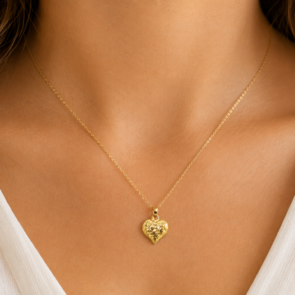 A 9ct gold patterned heart pendant on female