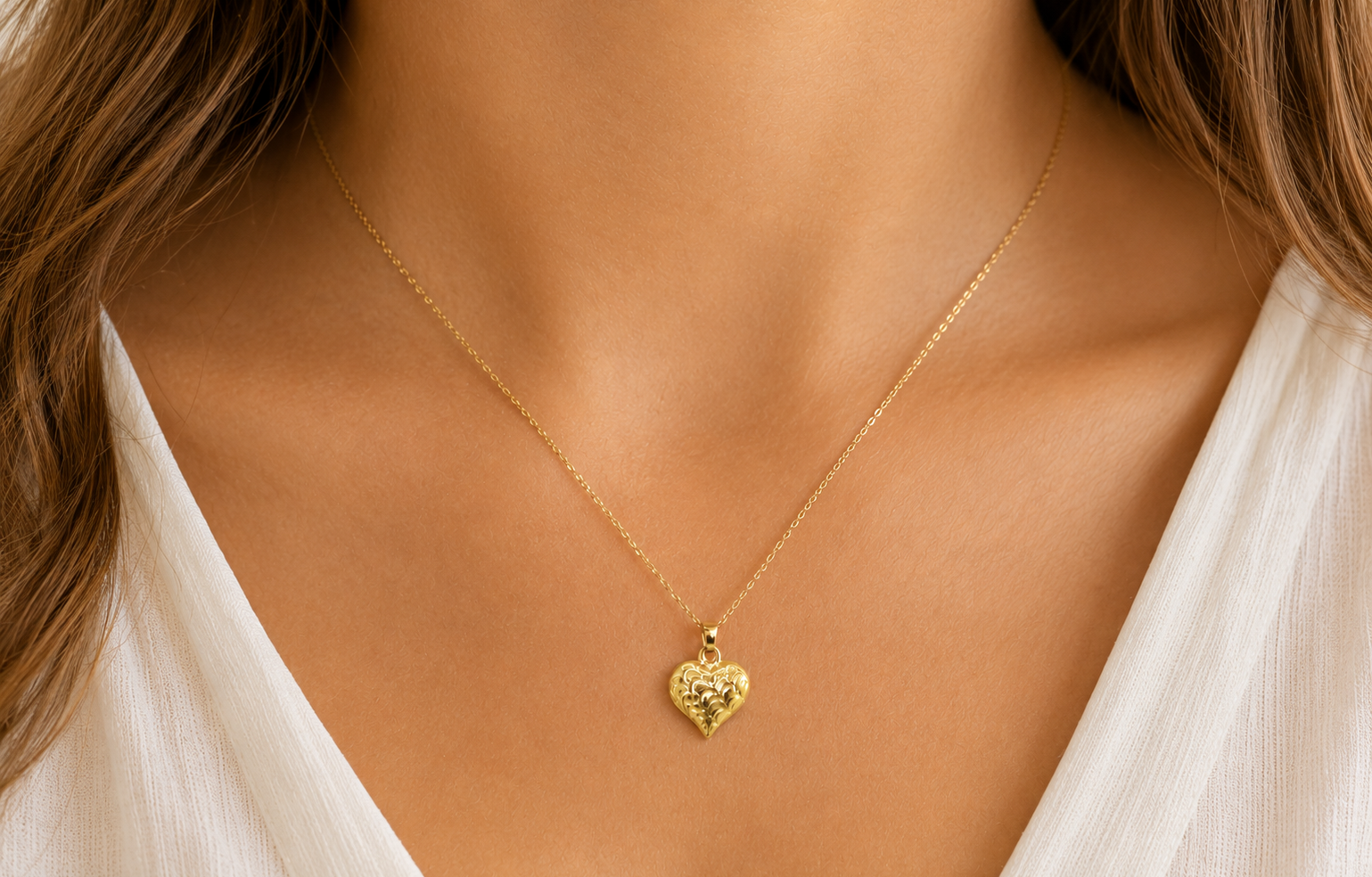 A 9ct gold patterned heart pendant on female
