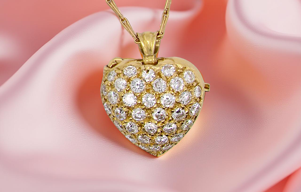 Gold heart-shaped pendant with diamonds on a pink fabric background