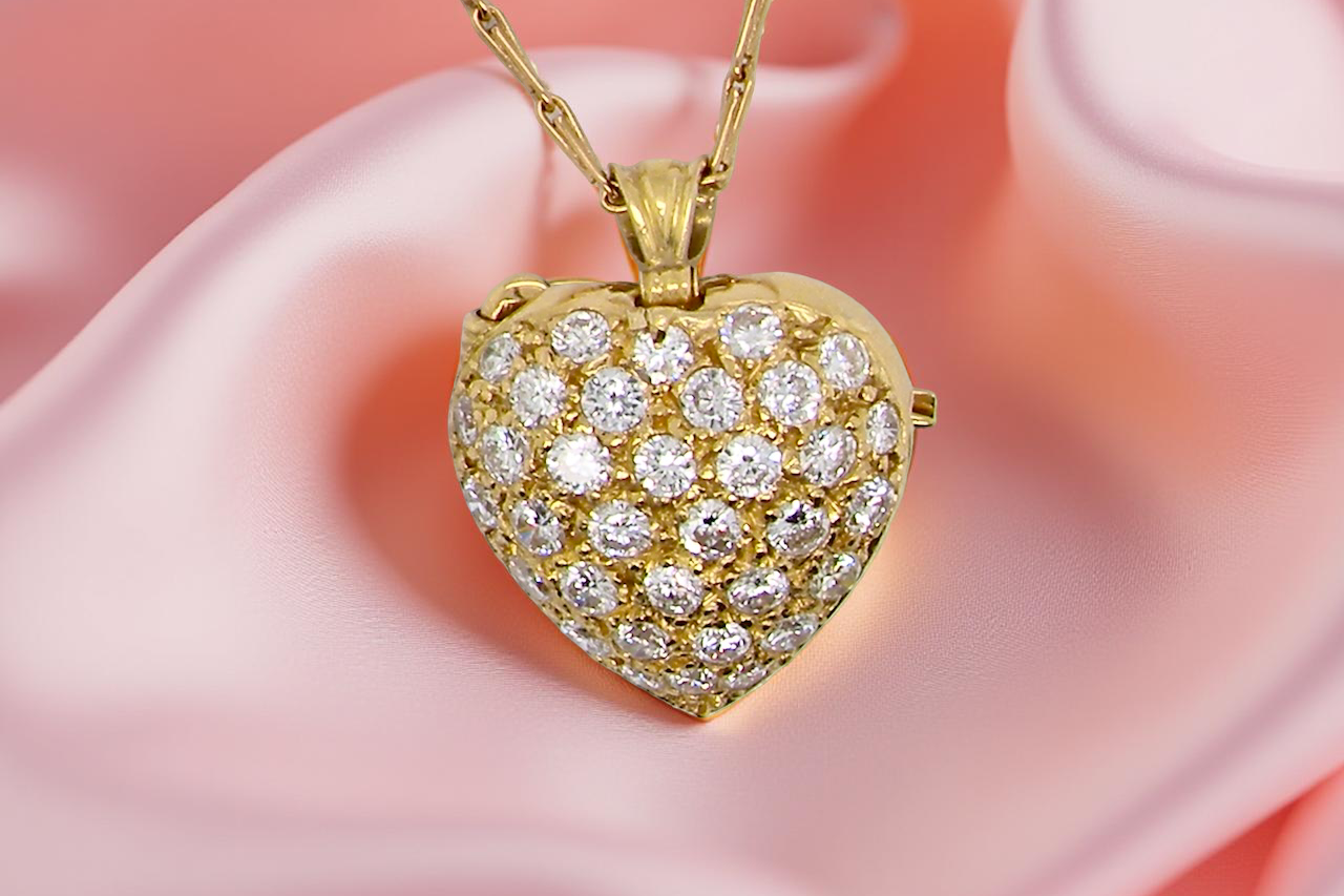 Gold heart-shaped pendant with diamonds on a pink fabric background