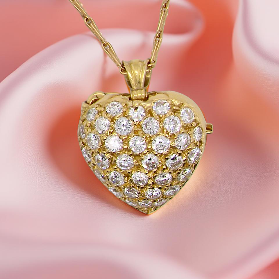 Gold heart-shaped pendant with diamonds on a pink fabric background