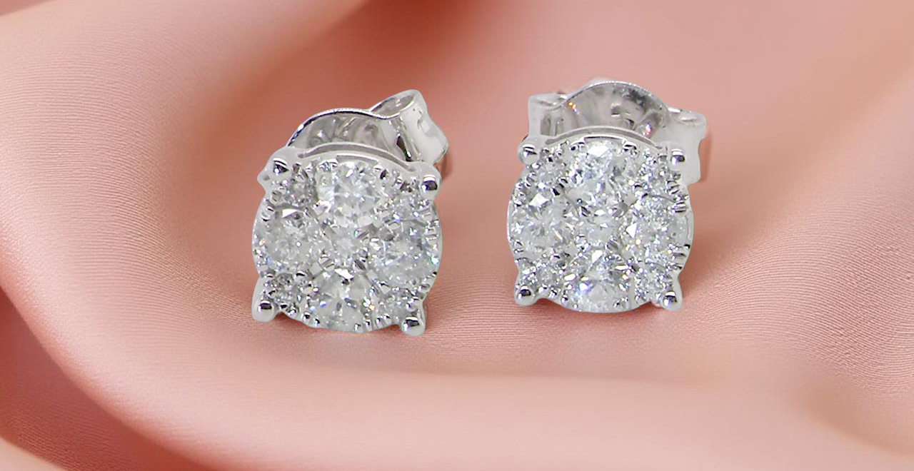Diamond stud earrings on a person's ear with a soft pink background