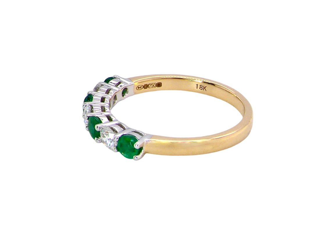 A NEW seven stone half hoop eternity ring. Set with four round emeralds, each 2.8mm (