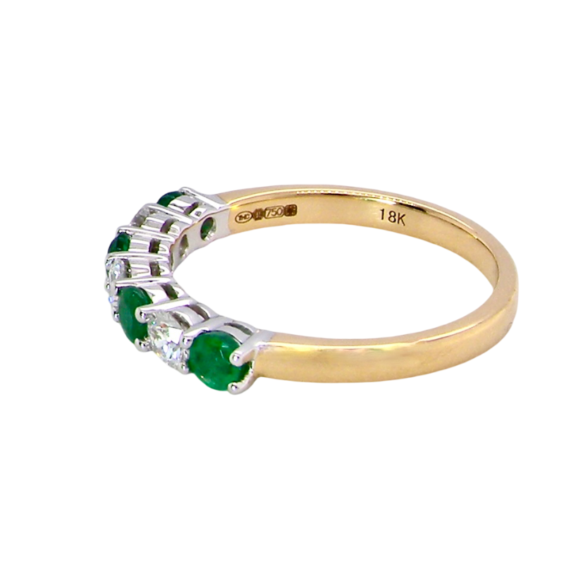 A NEW seven stone half hoop eternity ring. Set with four round emeralds, each 2.8mm (