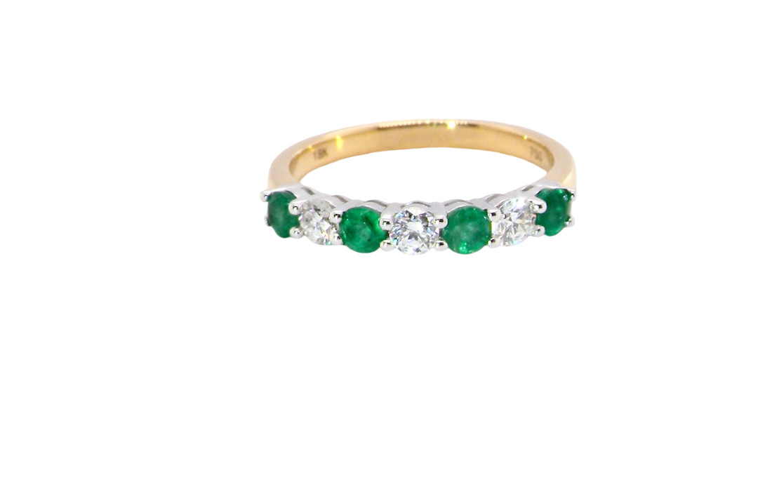 A NEW seven stone half hoop eternity ring. Set with four round emeralds, each 2.8mm (total 0.40 carats)